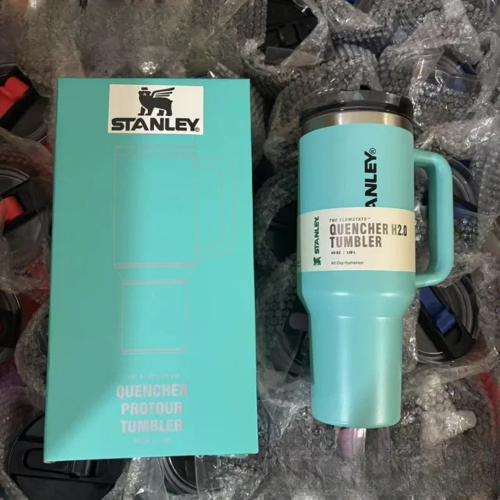 Turquoise Stanley tumbler with packaging on a gray background