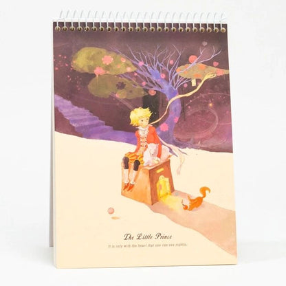 Calendar with an illustration of 'The Little Prince' sitting on a box with a fox and a tree in the background.