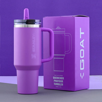 Purple Stanley tumbler with handle next to its packaging on a purple background