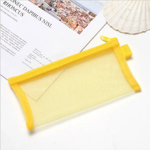 A collection of transparent mesh zipper pencil cases in various colors, displayed on a table with a decorative flower beside them.