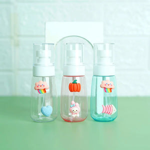 Three transparent mini pocket spray bottles with 3D cartoon stickers, displayed on a green surface. From left to right, the bottles have different colored liquid levels and are refillable.
