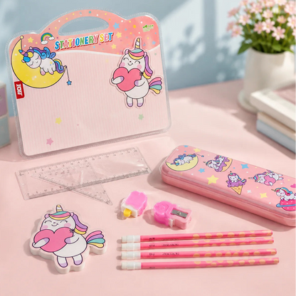 A pastel pink unicorn-themed stationery set arranged on a pink tabletop, including a carrying case, pencil case, pencils, eraser, ruler, sharpener, and a unicorn-shaped eraser. The items feature cartoon unicorns, moons, stars, and hearts in soft pink, yellow, purple, and white tones.