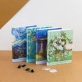 A collection of A5-sized journals with Van Gogh artwork on the covers, displayed alongside paper clips and a small notepad.