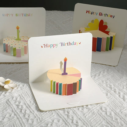 Three 'Happy Birthday' greeting cards with 3D cake designs on a textured surface.