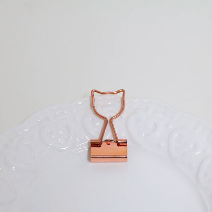 Rose gold binder clip on a white background