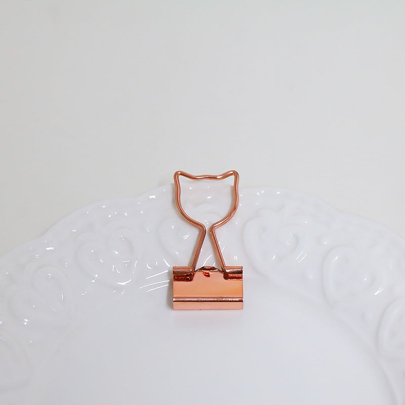 Rose gold binder clip on a white background