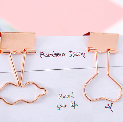 Rose gold cloud-shaped paper clips on a notebook with 'Rainbow Diary' text.