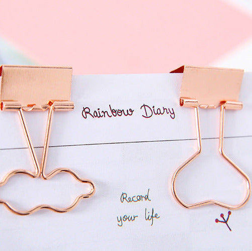 Rose gold cloud-shaped paper clips on a notebook with 'Rainbow Diary' text.