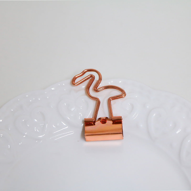 Rose gold binder clip on a white surface