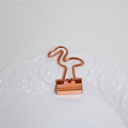 Rose gold binder clip on a white surface