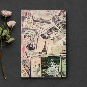 Notebook with vintage-style collage cover on a dark surface with flowers.