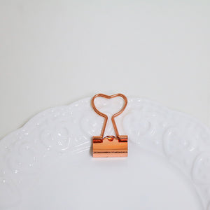 Rose gold heart-shaped clip on a white surface