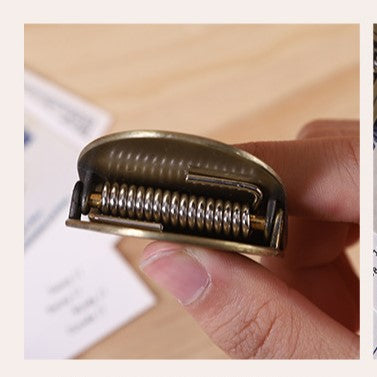 Close-up of a metallic object held between fingers on a wooden surface