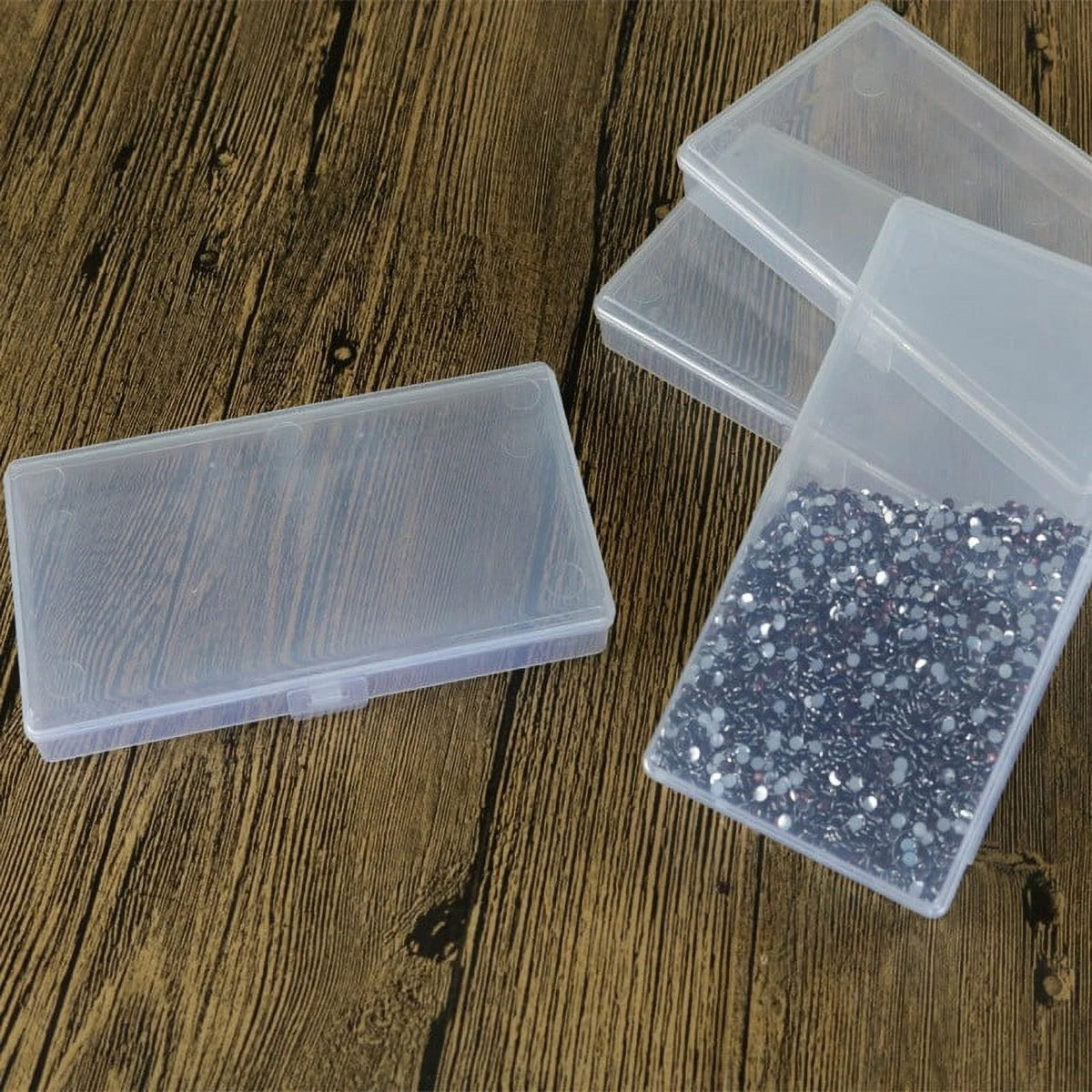 Clear plastic containers with one having glittery contents on a wooden surface