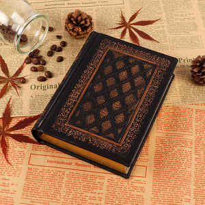 A journal with a decorative, embossed cover featuring a geometric pattern, placed on a surface with pine cones and coffee beans, suggesting its use for writing or recording personal thoughts.
