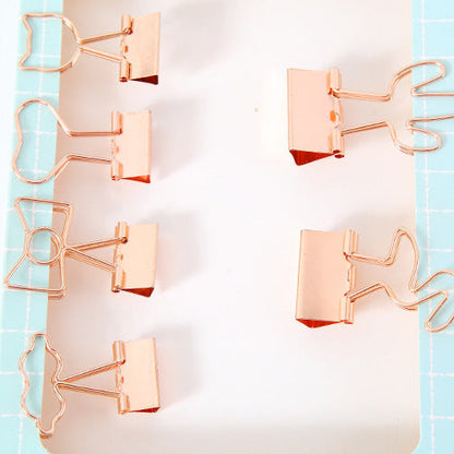 Rose gold paper clips on a light blue and white striped background