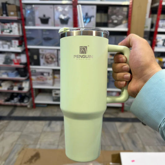 Light green insulated mug with handle held by a person in a store setting