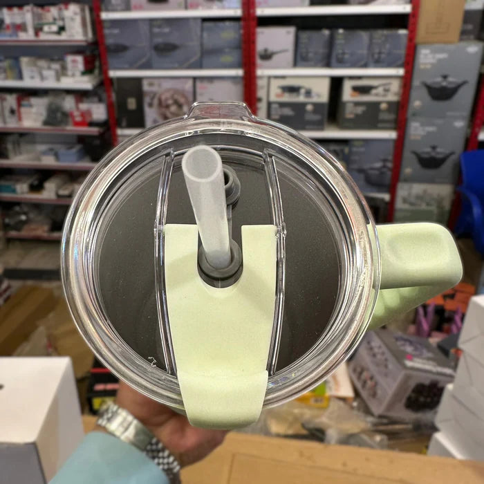 Clear lid with a straw and green handle held in front of a store shelf.