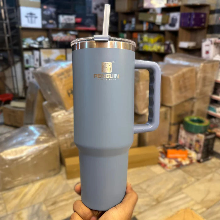 Gray insulated mug with handle held in front of a warehouse setting