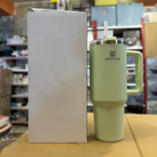 Light green insulated mug with handle and straw lid next to a white box in a store setting