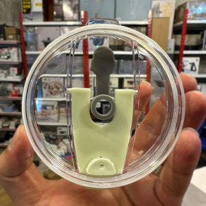 Clear lid with green base held in a hand against a store background