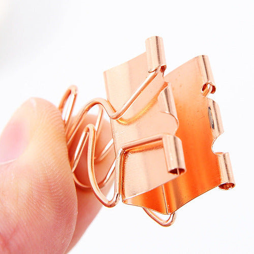 Rose gold paper clip held by a hand on a white background