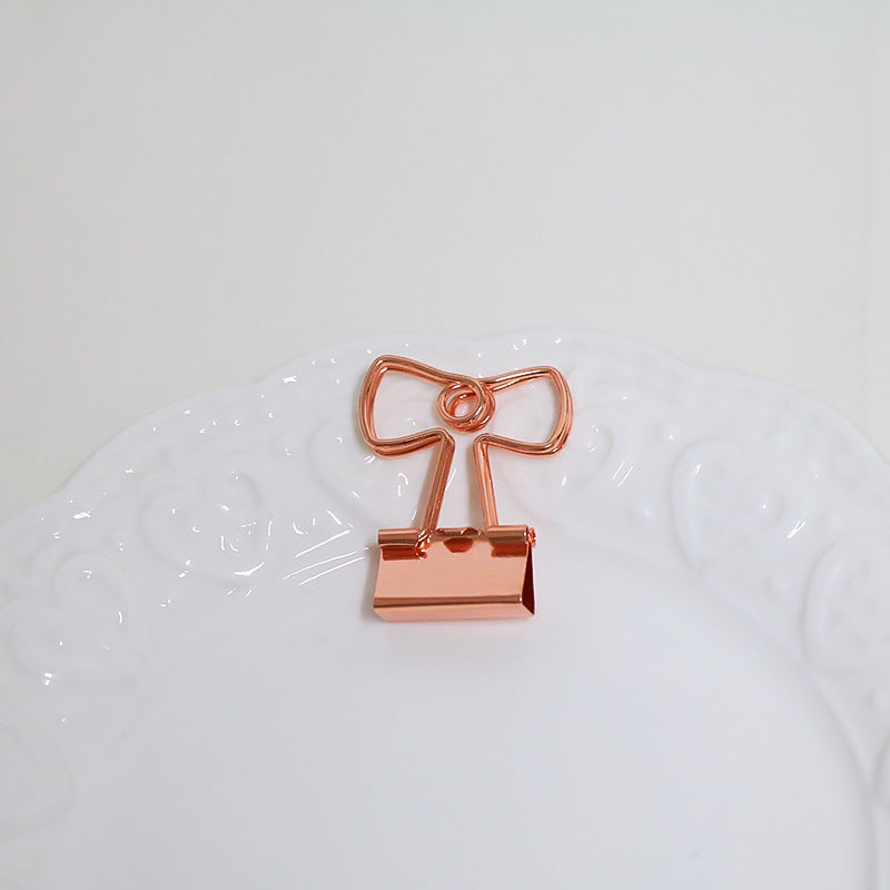 Rose gold bow-shaped clip on a white background