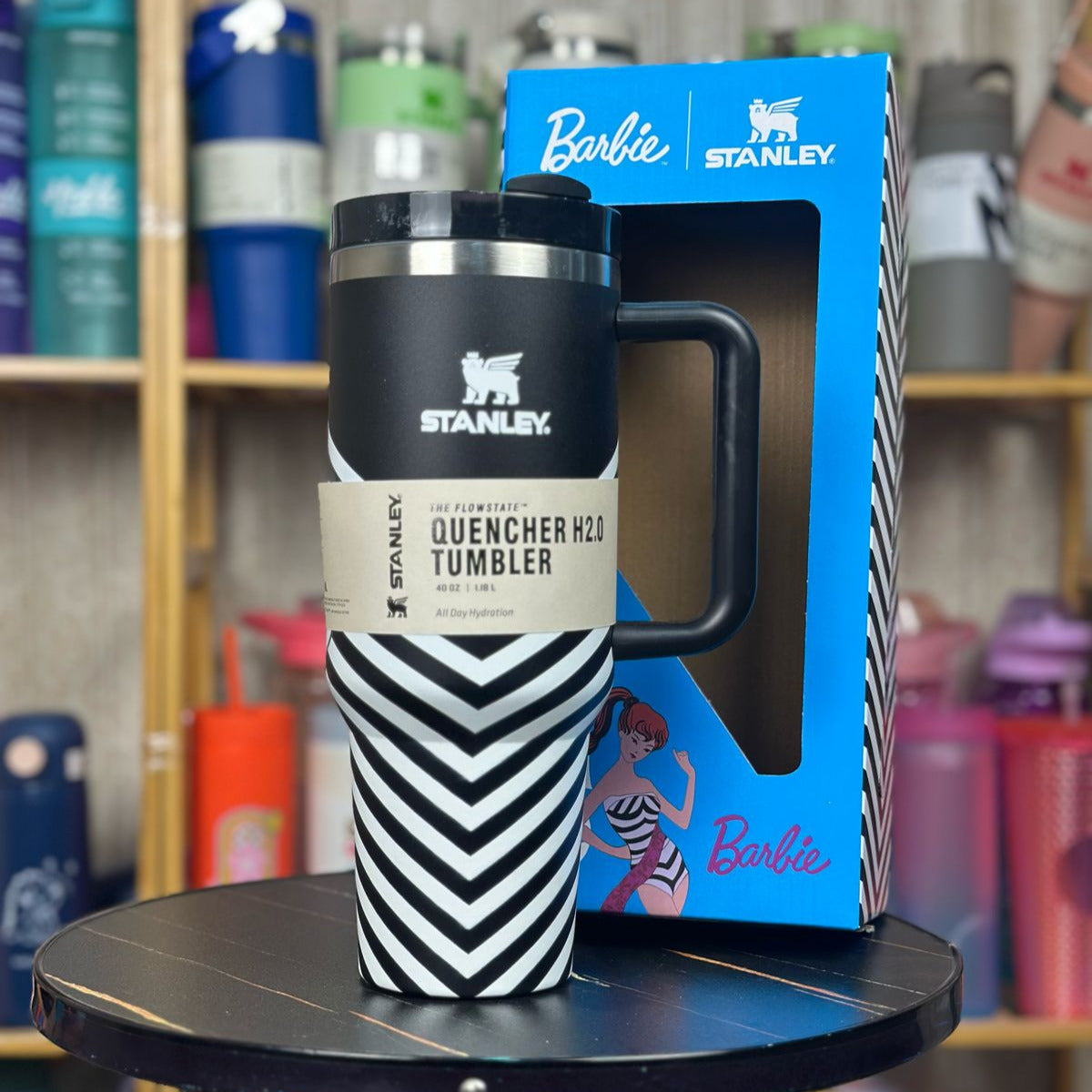 Stanley tumbler with black and white chevron pattern on a small round table, with a Barbie Stanley packaging box in the background.