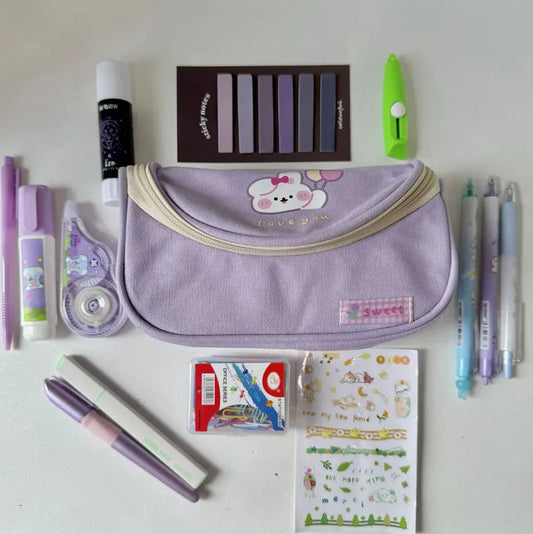 Assorted stationery items including a purple pouch, pens, markers, and stickers on a white background.