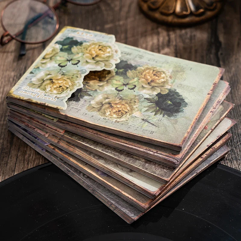 Stack of vintage-style photo albums with floral designs on a wooden surface.