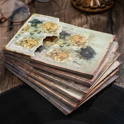 Stack of vintage-style photo albums with floral designs on a wooden surface.