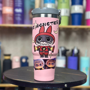 Pink tumbler with cartoon character design on a table with blurred colorful background
